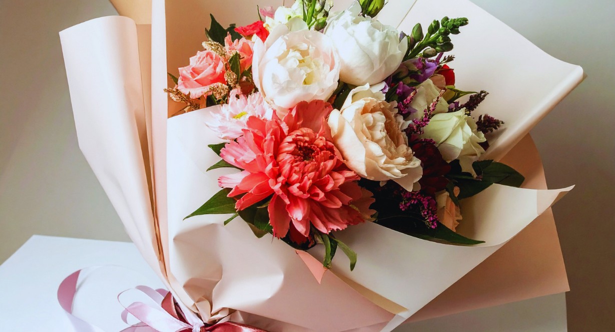 Bouquet de fleurs pastel offert dans un emballage cadeau